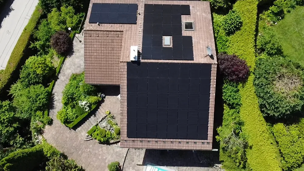Einfamilienhaus von oben mit drei Feldern schwarzer Photovoltaik-Module