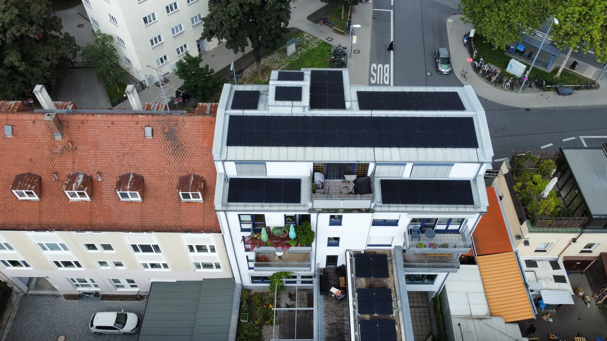 Wohn- und Geschäftshaus mit Photovoltaik auf dem Dach, Luftaufnahme von vorne